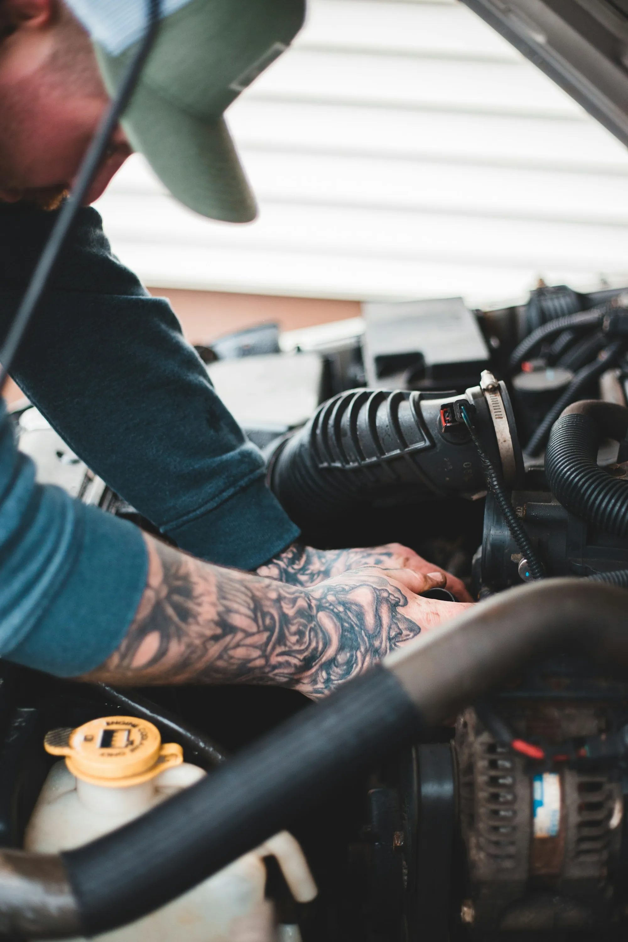 Mechanic with tattooed forearms working on an engine