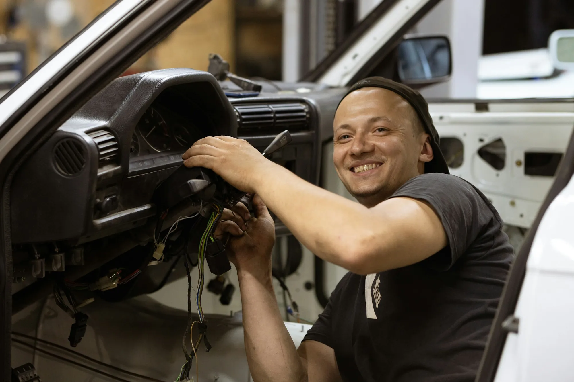 Smiling mechanic working under the dashboard of a car