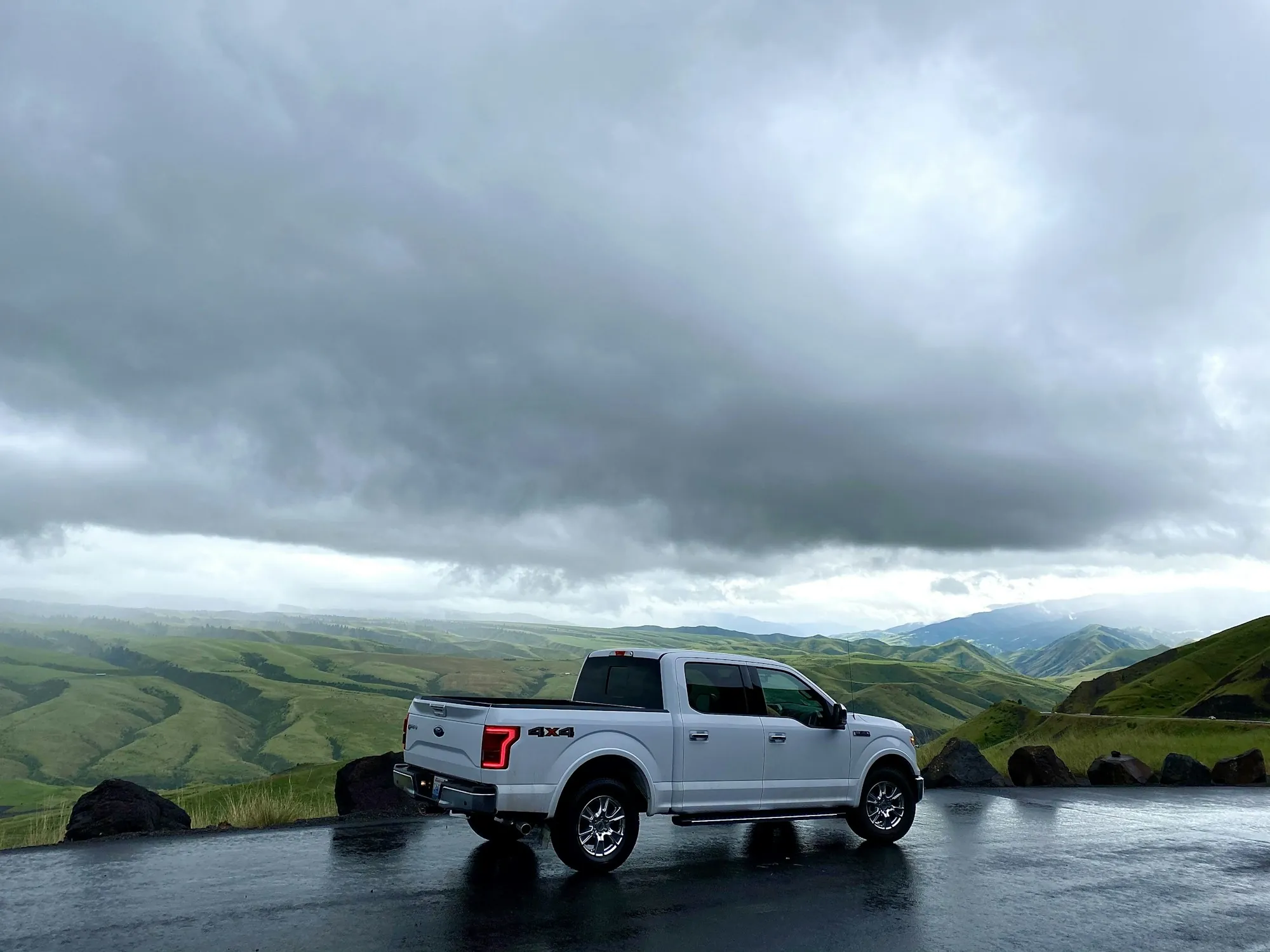 White pickup on a hillside road under heavy grey clouds