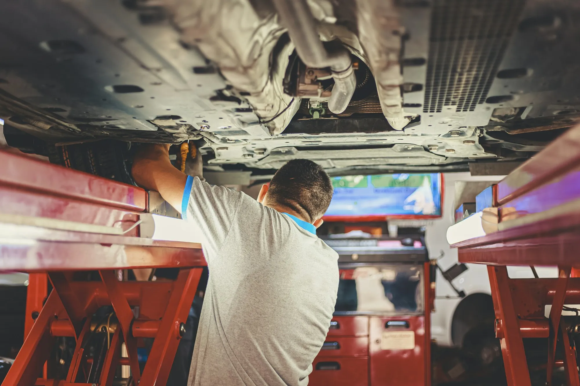 Technician working under a car raised on a red lift