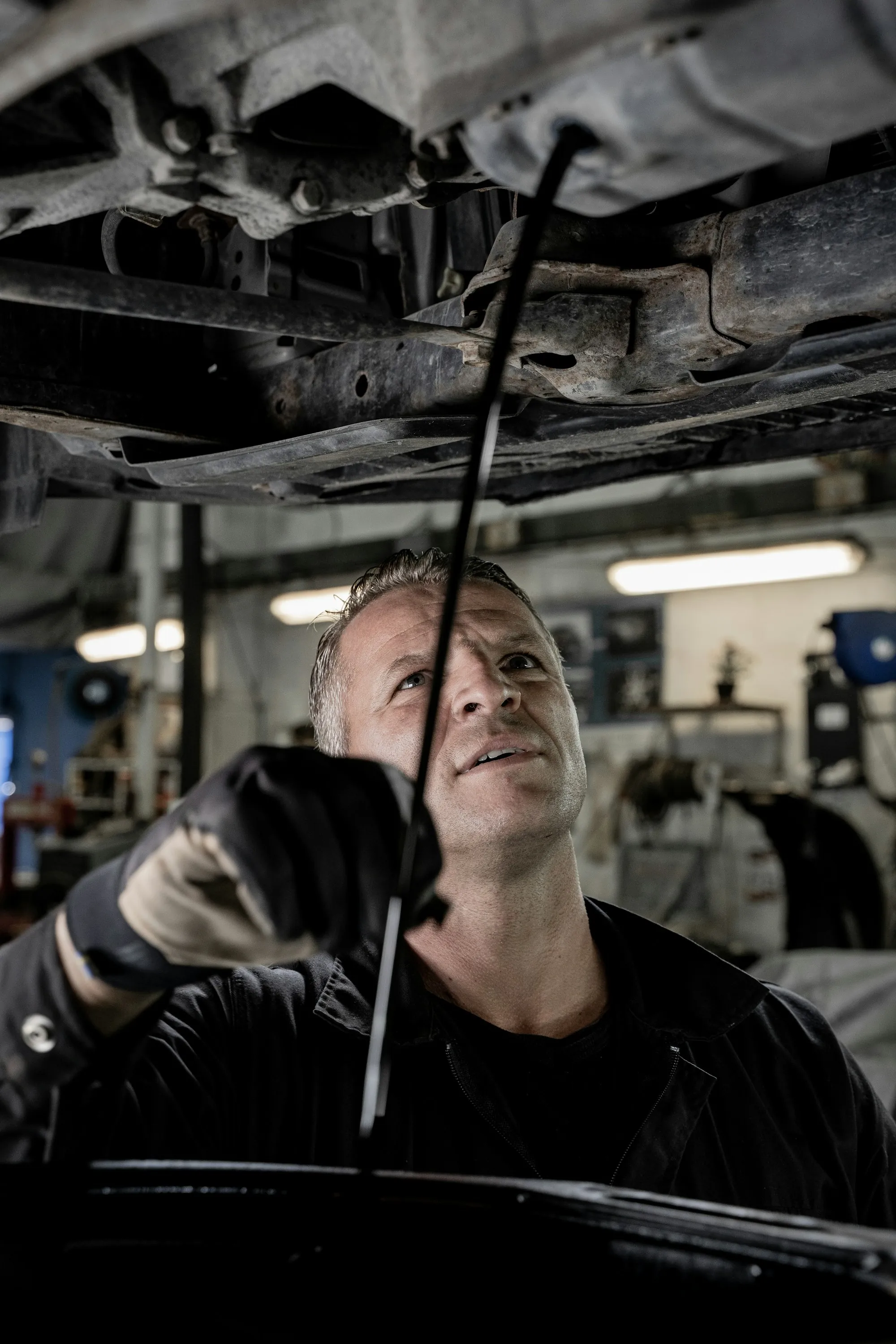 Mechanic working on a vehicle beneath its raised hood